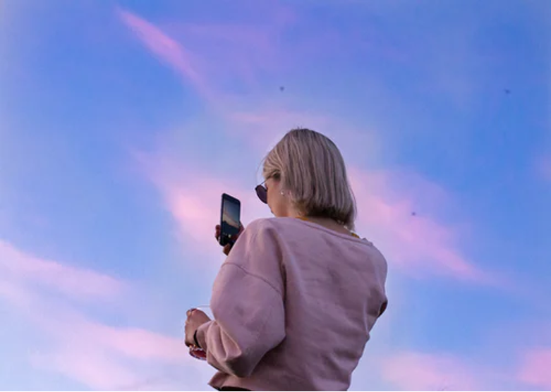 Woman looking at iphone with blue sky background